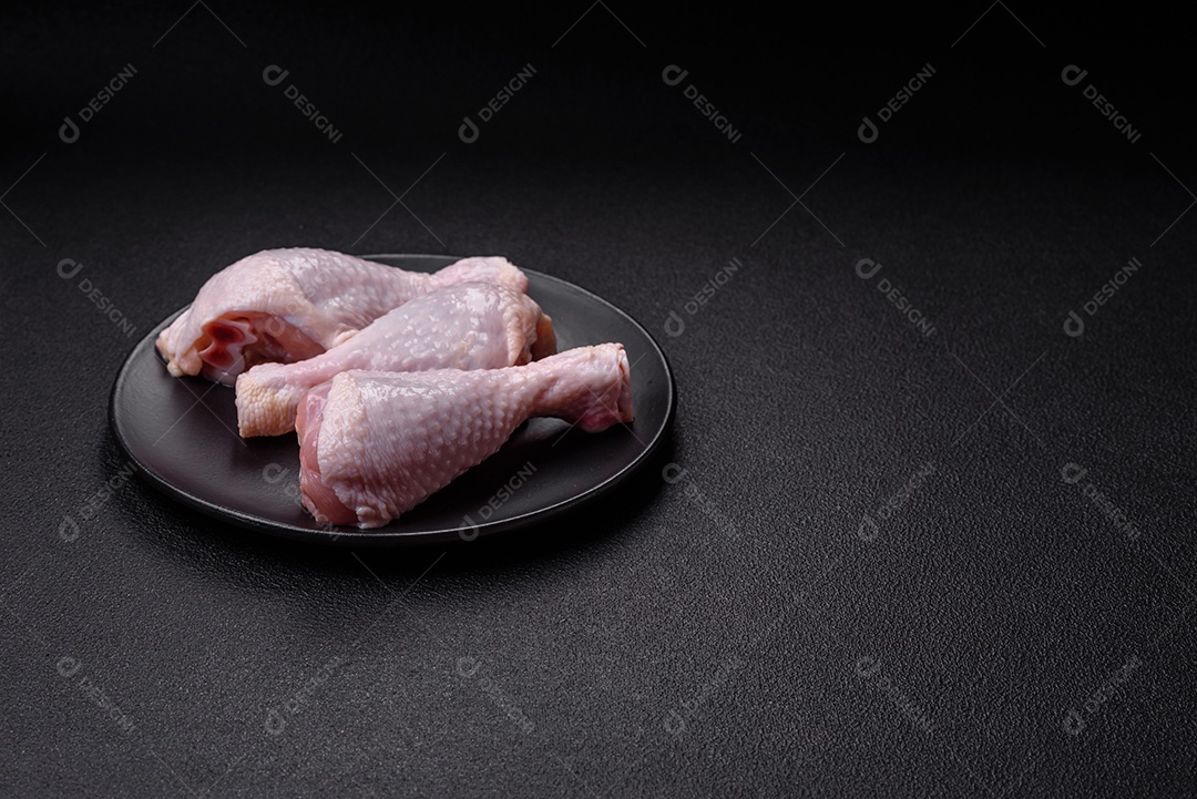 Coxas de frango cru fresco com sal e especiarias em fundo escuro de concreto