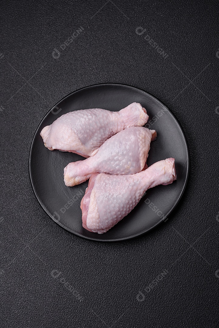 Coxas de frango cru fresco com sal e especiarias em fundo escuro de concreto