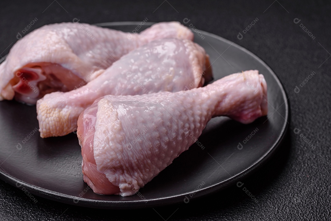 Coxas de frango cru fresco com sal e especiarias em fundo escuro de concreto