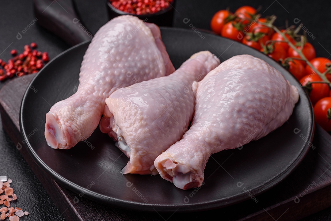 Coxas de frango cru fresco com sal e especiarias em fundo escuro de concreto