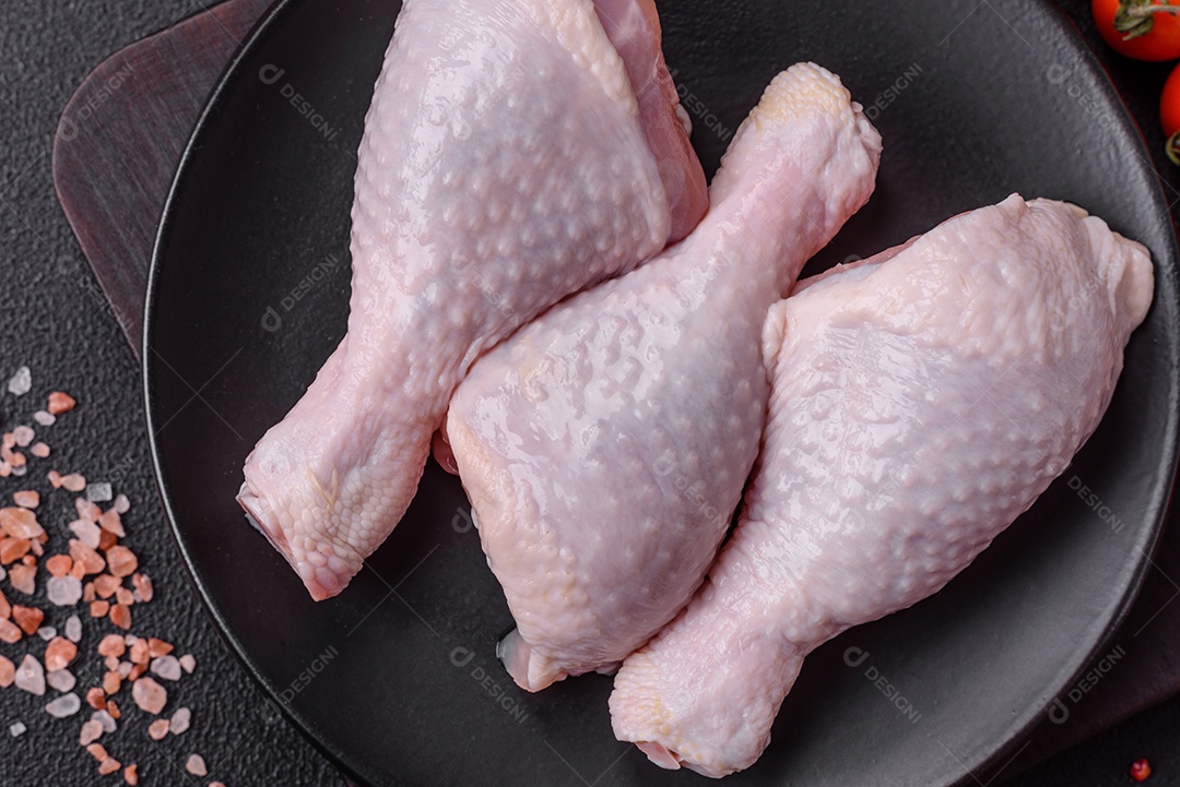 Coxas de frango cru fresco com sal e especiarias em fundo escuro de concreto