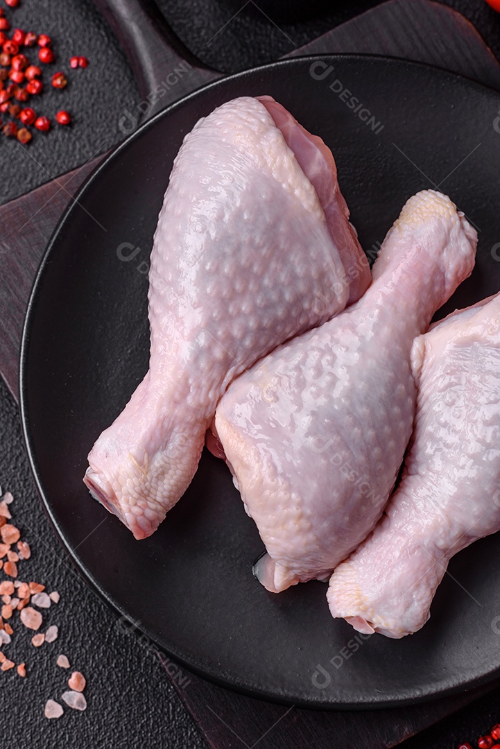 Coxas de frango cru fresco com sal e especiarias em fundo escuro de concret