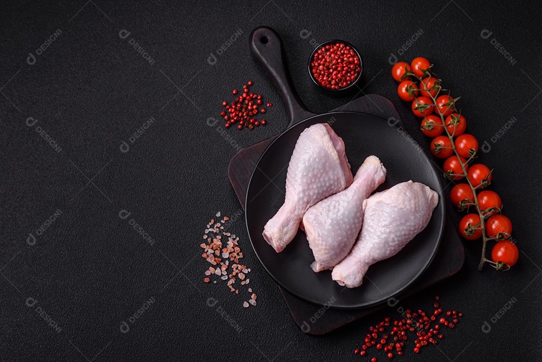Coxas de frango cru fresco com sal e especiarias em fundo escuro de concreto