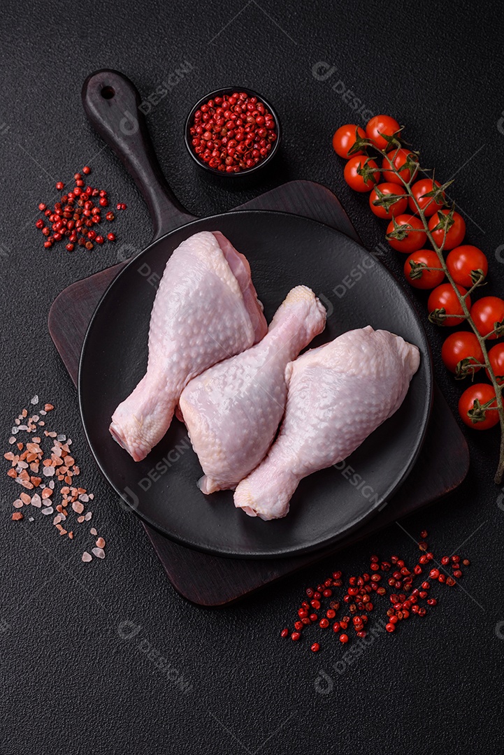 Coxas de frango cru fresco com sal e especiarias em fundo escuro de concreto