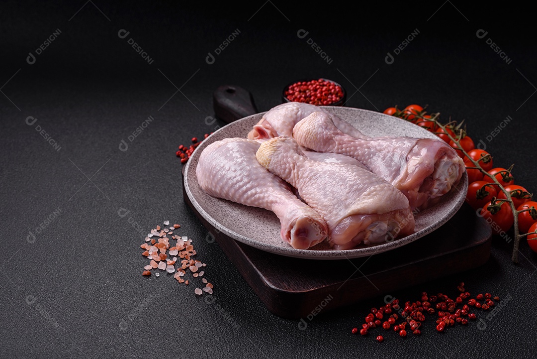 Coxas de frango cru fresco com sal e especiarias em fundo escuro de concreto