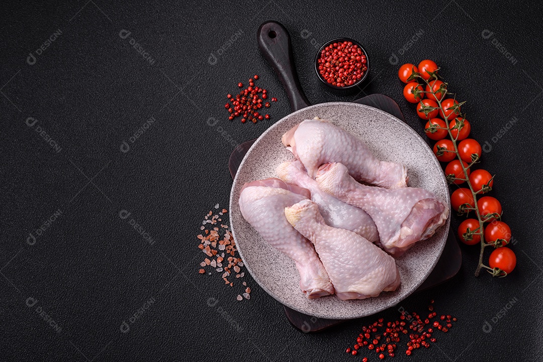 Coxas de frango cru fresco com sal e especiarias em fundo escuro de concreto