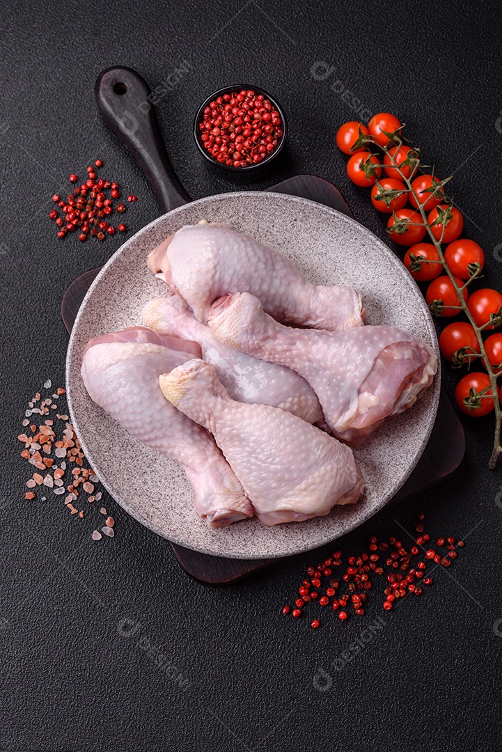 Coxas de frango cru fresco com sal e especiarias em fundo escuro de concreto