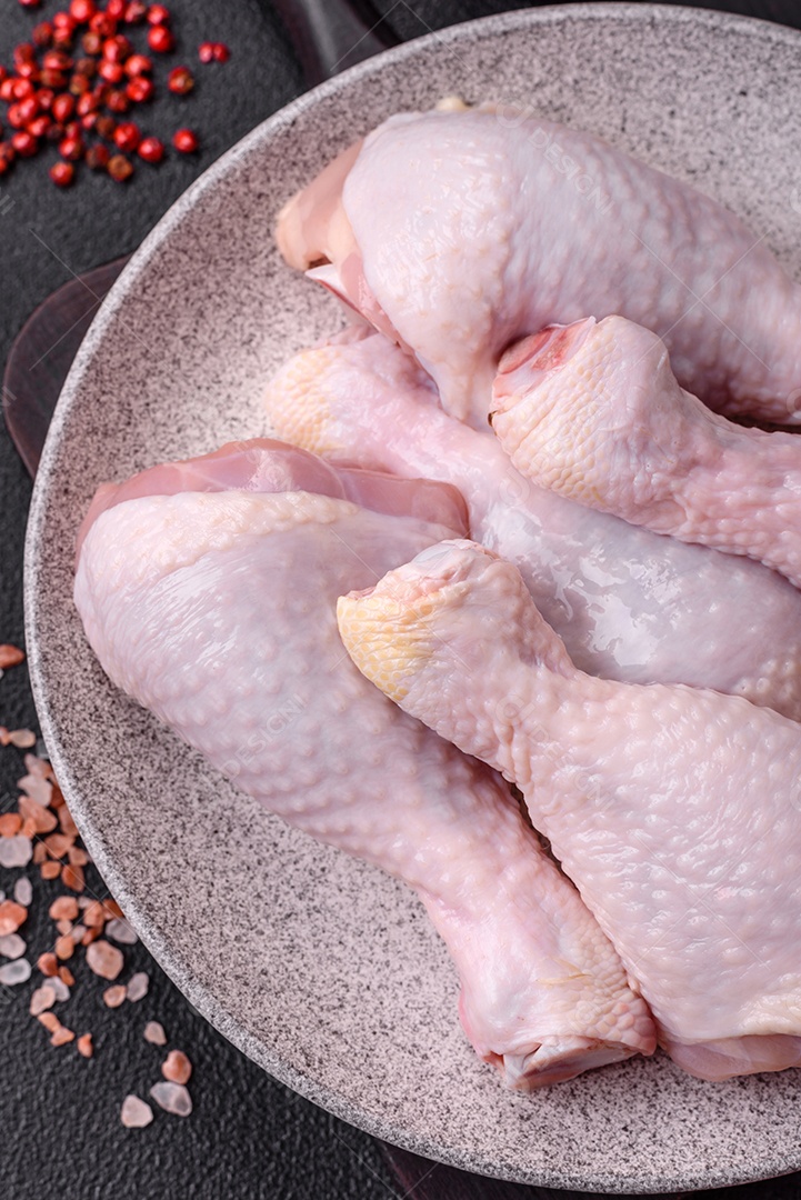 Coxas de frango cru fresco com sal e especiarias em fundo escuro de concreto