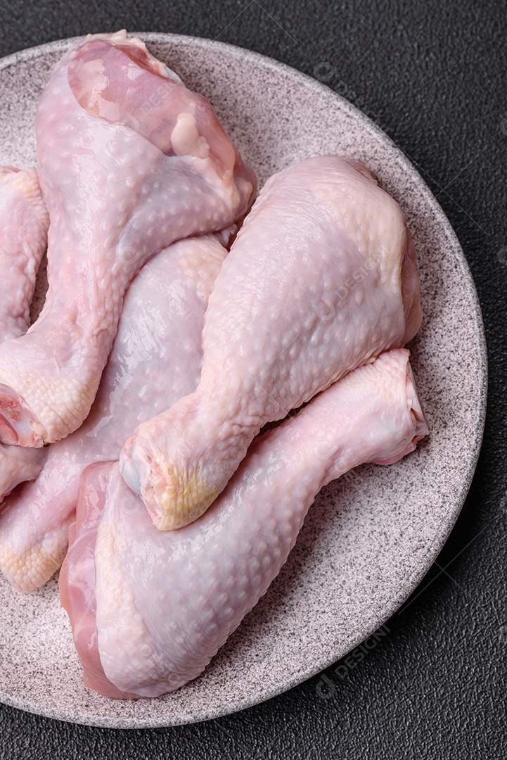 Coxas de frango cru fresco com sal e especiarias em fundo escuro de concreto