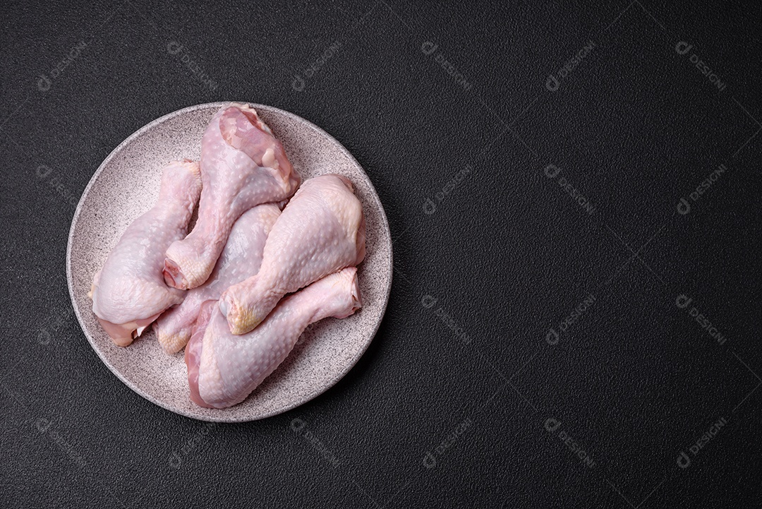 Coxas de frango cru fresco com sal e especiarias em fundo escuro de concreto