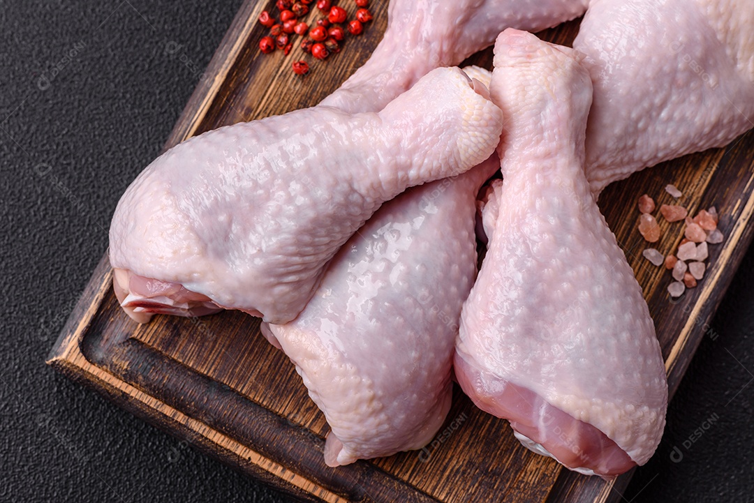 Coxas de frango cru fresco com sal e especiarias em fundo escuro de concreto