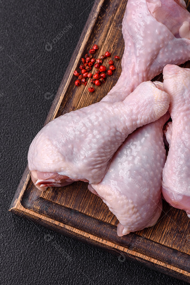 Coxas de frango cru fresco com sal e especiarias em fundo escuro de concreto