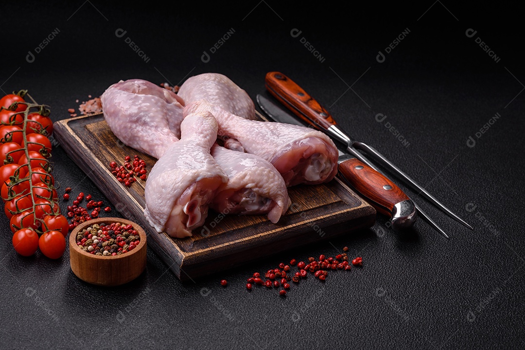 Coxas de frango cru fresco com sal e especiarias em fundo escuro de concreto