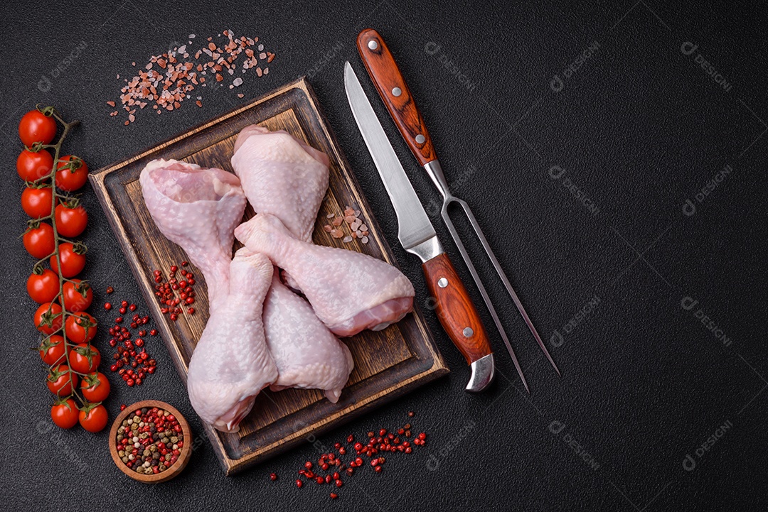 Coxas de frango cru fresco com sal e especiarias em fundo escuro de concreto