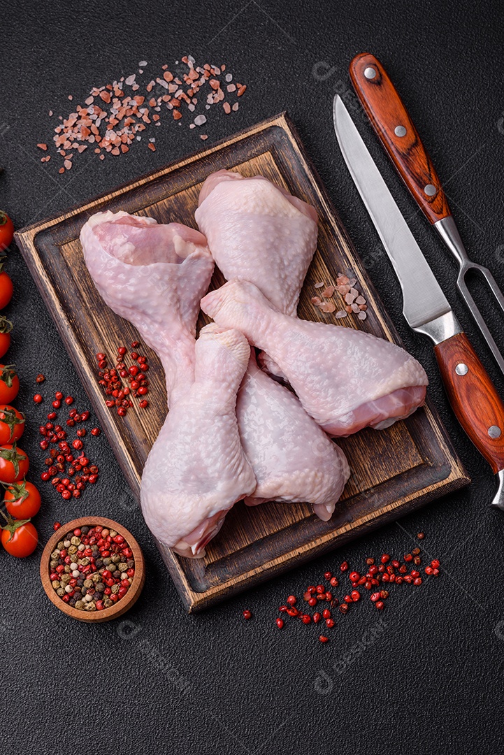 Coxas de frango cru fresco com sal e especiarias em fundo escuro de concreto