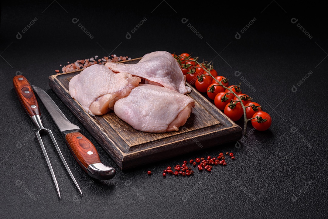 Coxas de frango cru fresco com sal e especiarias em fundo escuro de concreto