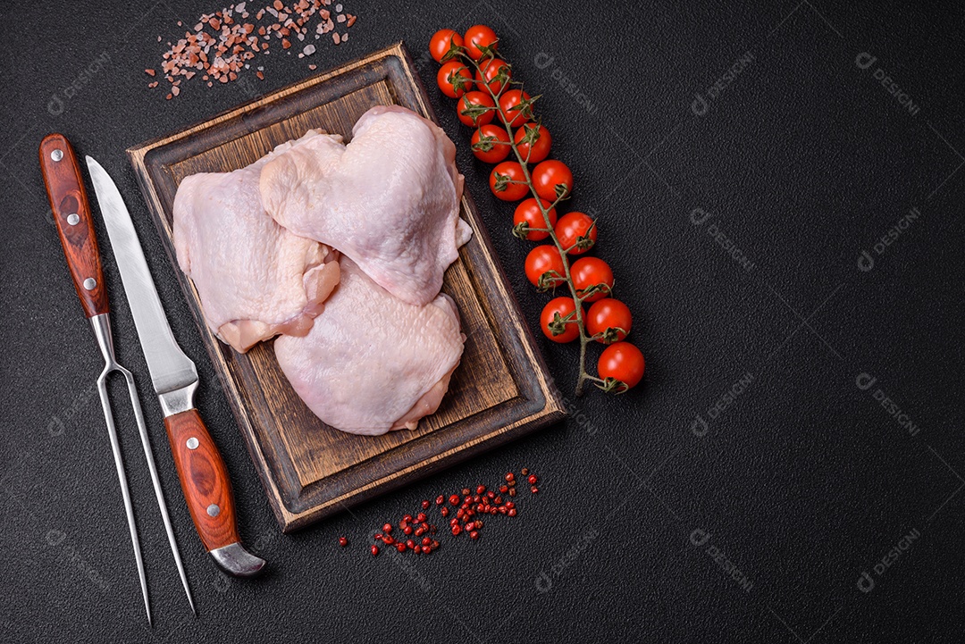 Coxas de frango cru fresco com sal e especiarias em fundo escuro de concreto