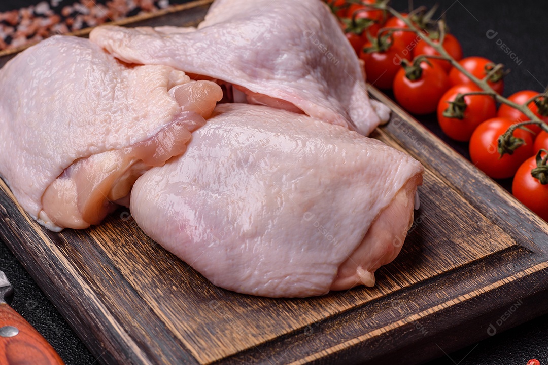 Coxas de frango cru fresco com sal e especiarias em fundo escuro de concreto