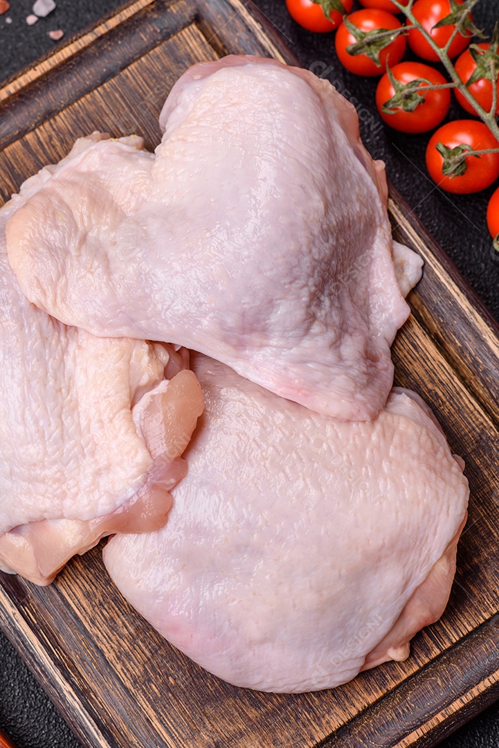 Coxas de frango cru fresco com sal e especiarias em fundo escuro de concreto