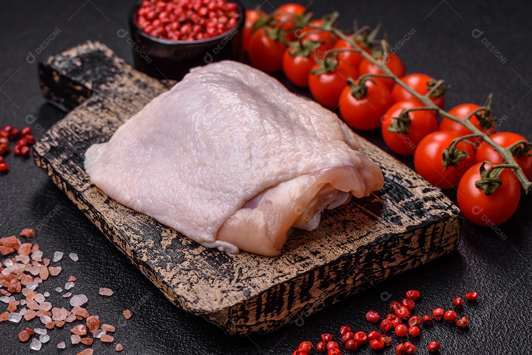 Coxas de frango cru fresco com sal e especiarias em fundo escuro de concreto