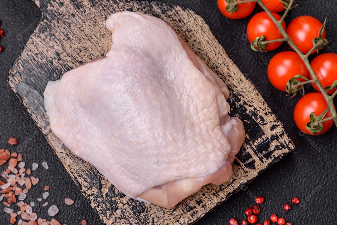 Coxas de frango cru fresco com sal e especiarias em fundo escuro de concreto