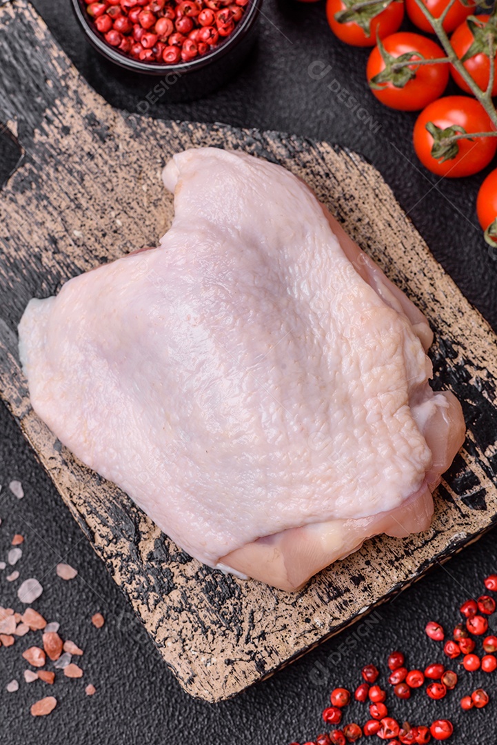 Coxas de frango cru fresco com sal e especiarias em fundo escuro de concreto