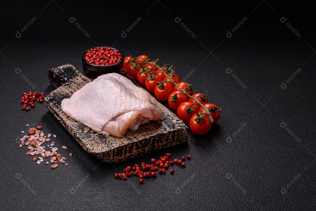 Coxas de frango cru fresco com sal e especiarias em fundo escuro de concreto