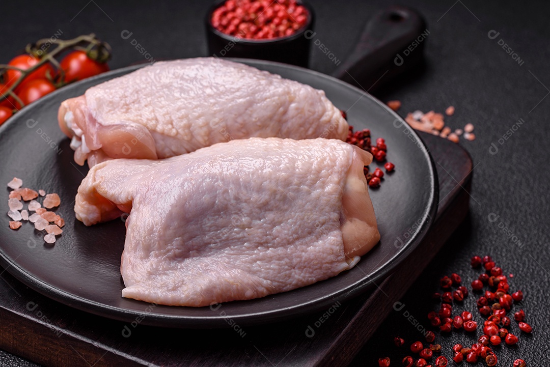 Coxas de frango cru fresco com sal e especiarias em fundo escuro de concreto