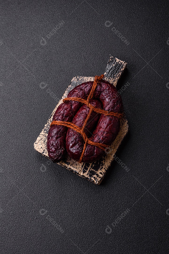 Delicioso chouriço preto ou morcela com especiarias e ervas grelhadas sobre fundo de concreto preto