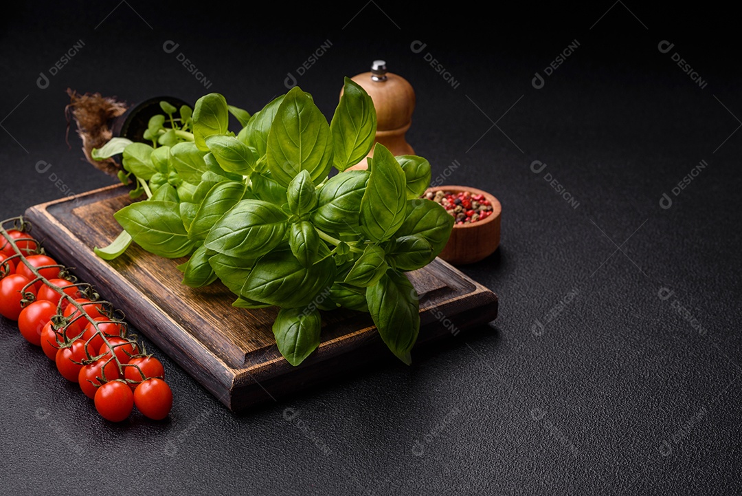 Manjericão de ervas frescas em forma de arbusto como ingrediente para cozinhar em casa sobre um fundo escuro de concreto