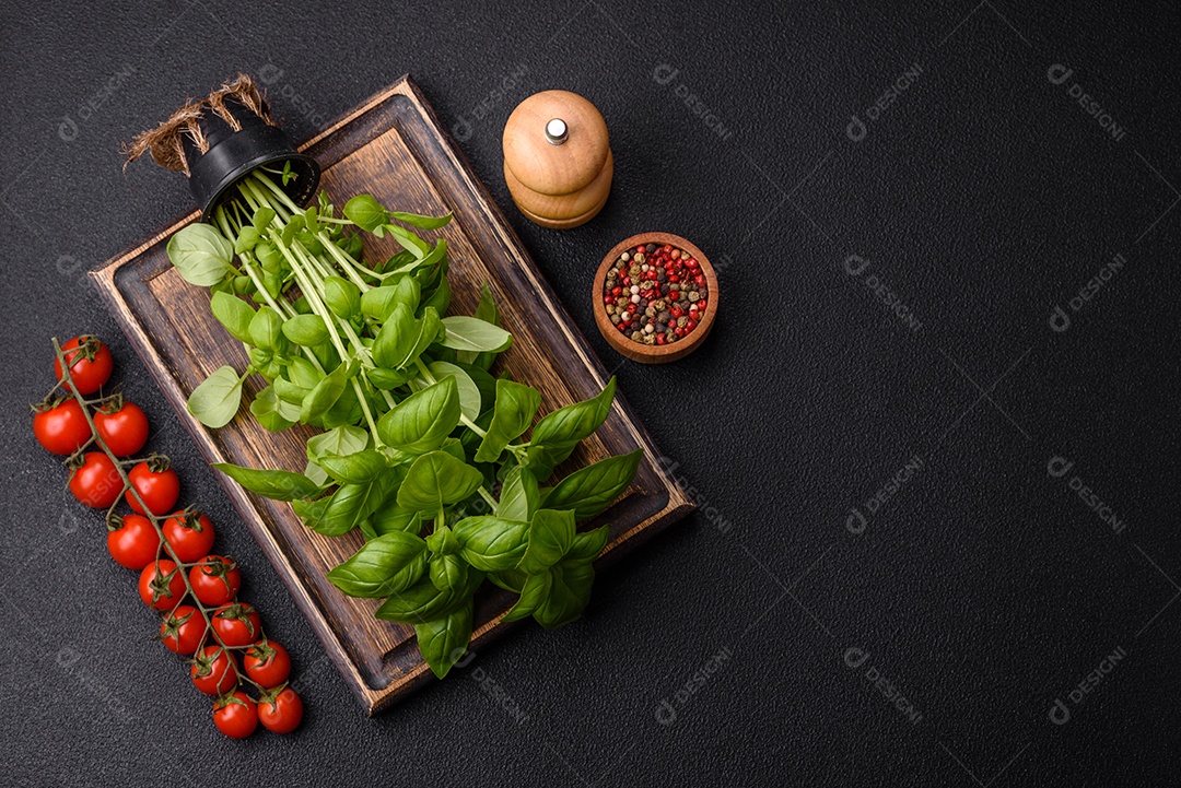 Manjericão de ervas frescas em forma de arbusto como ingrediente para cozinhar em casa sobre um fundo escuro de concreto