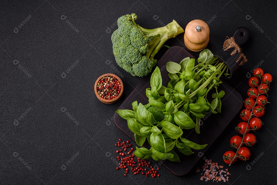 Manjericão de ervas frescas em forma de arbusto como ingrediente para cozinhar em casa sobre um fundo escuro de concreto