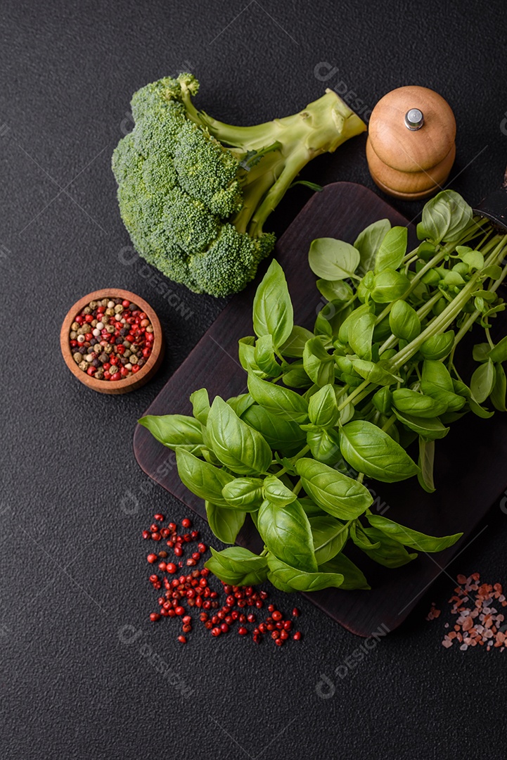 Manjericão de ervas frescas em forma de arbusto como ingrediente para cozinhar em casa sobre um fundo escuro de concreto