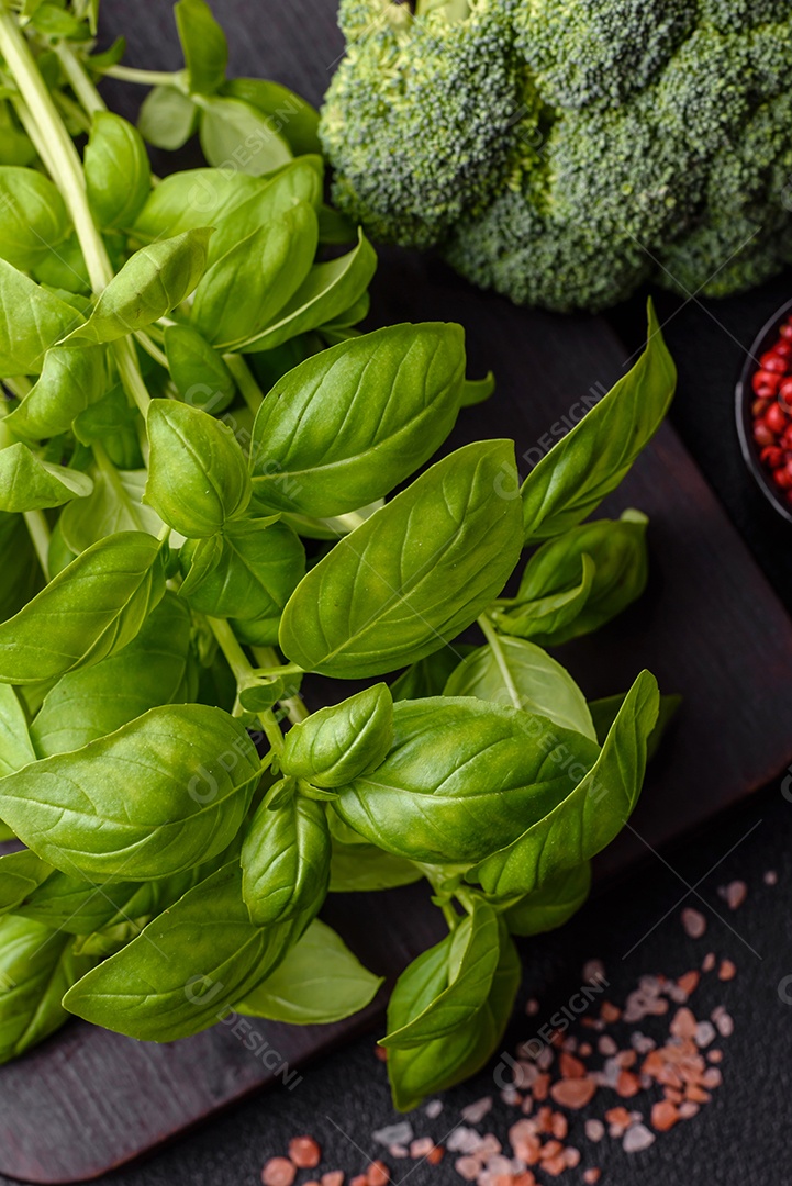 Manjericão de ervas frescas em forma de arbusto como ingrediente para cozinhar em casa sobre um fundo escuro de concreto