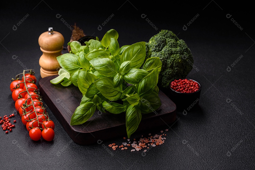 Manjericão de ervas frescas em forma de arbusto como ingrediente para cozinhar em casa sobre um fundo escuro de concreto