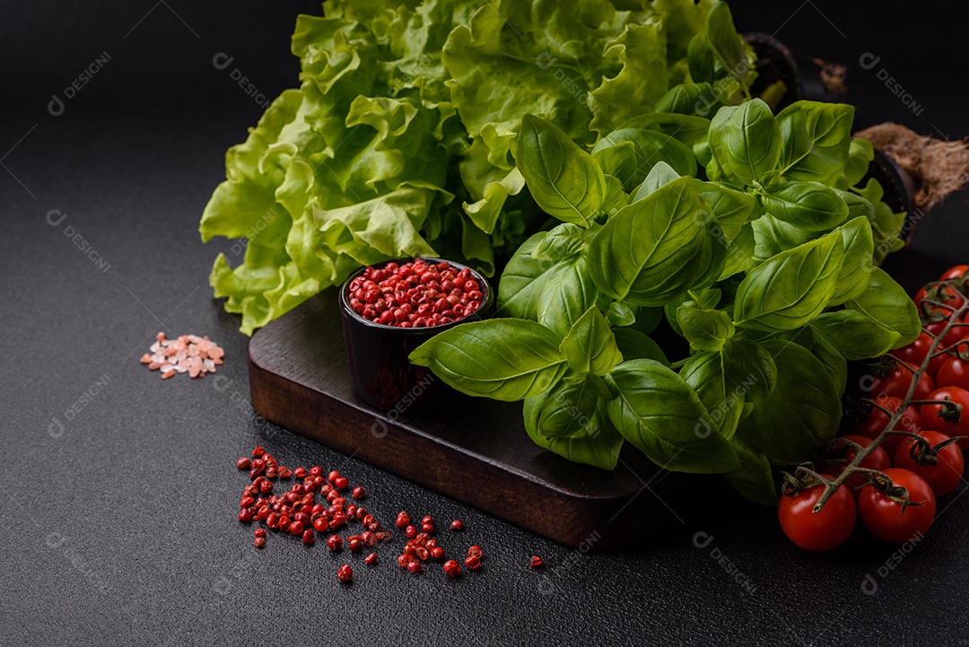 Manjericão de ervas frescas em forma de arbusto como ingrediente para cozinhar em casa sobre um fundo escuro de concreto
