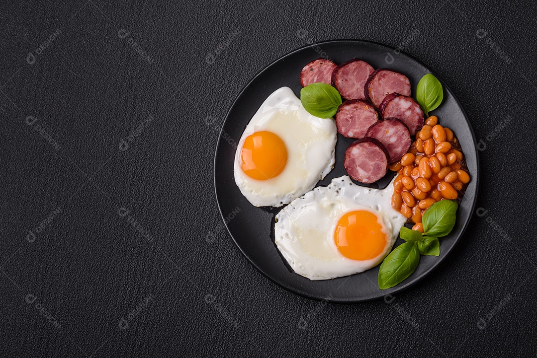 Café da manhã inglês com ovos fritos, bacon, feijão, tomate, especiarias e ervas. Um início de dia saudável e nutritivo