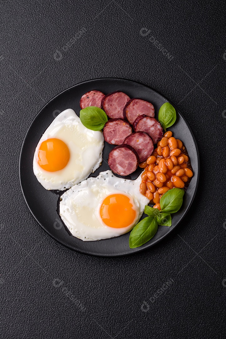 Café da manhã inglês com ovos fritos, bacon, feijão, tomate, especiarias e ervas. Um início de dia saudável e nutritivo