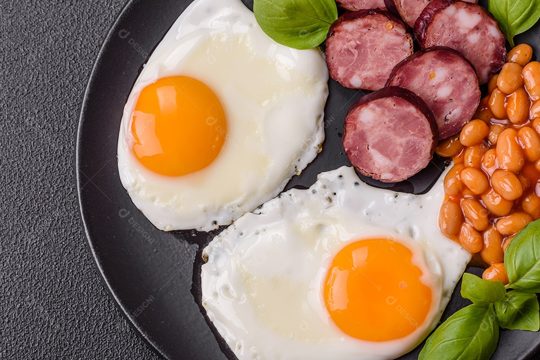 Café da manhã inglês com ovos fritos, bacon, feijão, tomate, especiarias e ervas. Um início de dia saudável e nutritivo