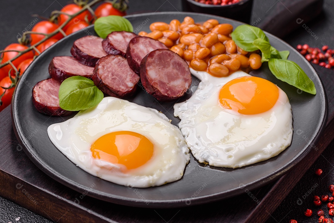 Café da manhã inglês com ovos fritos, bacon, feijão, tomate, especiarias e ervas. Um início de dia saudável e nutritivo