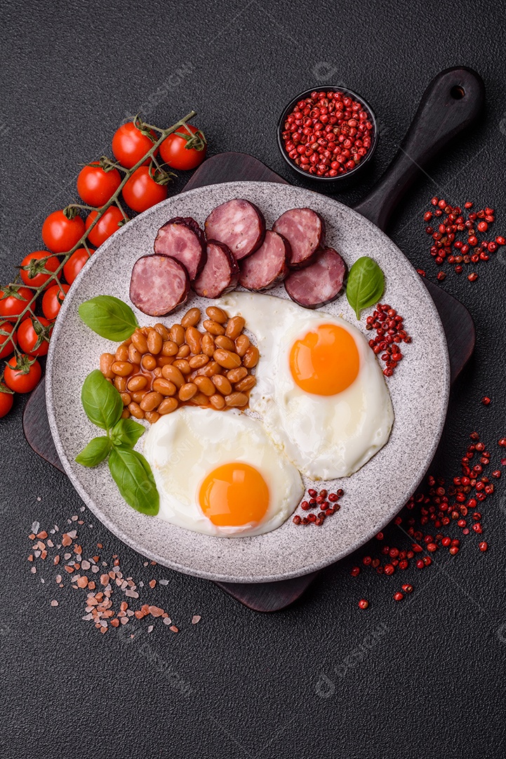 Café da manhã inglês com ovos fritos, bacon, feijão, tomate, especiarias e ervas. Um início de dia saudável e nutritivo