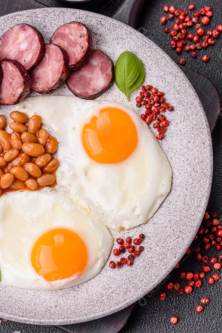 Café da manhã inglês com ovos fritos, bacon, feijão, tomate, especiarias e ervas. Um início de dia saudável e nutritivo