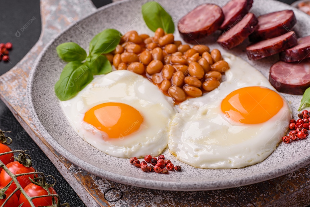 Café da manhã inglês com ovos fritos, bacon, feijão, tomate, especiarias e ervas. Um início de dia saudável e nutritivo