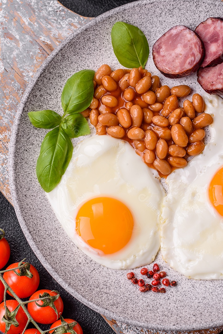 Café da manhã inglês com ovos fritos, bacon, feijão, tomate, especiarias e ervas. Um início de dia saudável e nutritivo