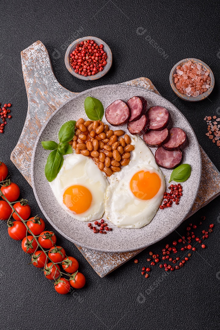 Café da manhã inglês com ovos fritos, bacon, feijão, tomate, especiarias e ervas. Um início de dia saudável e nutritivo