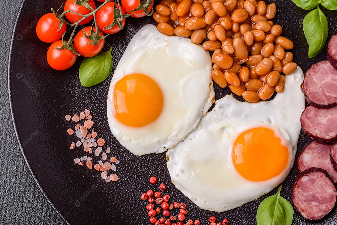 Café da manhã inglês com ovos fritos, bacon, feijão, tomate, especiarias e ervas. Um início de dia saudável e nutritivo