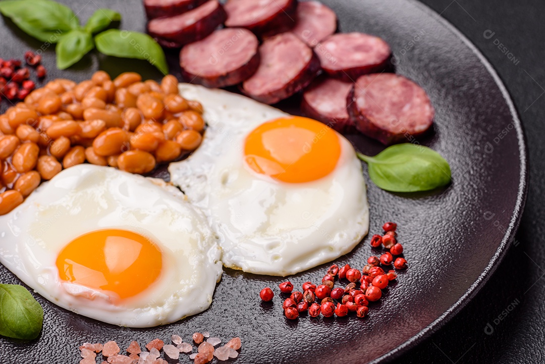 Café da manhã inglês com ovos fritos, bacon, feijão, tomate, especiarias e ervas. Um início de dia saudável e nutritivo