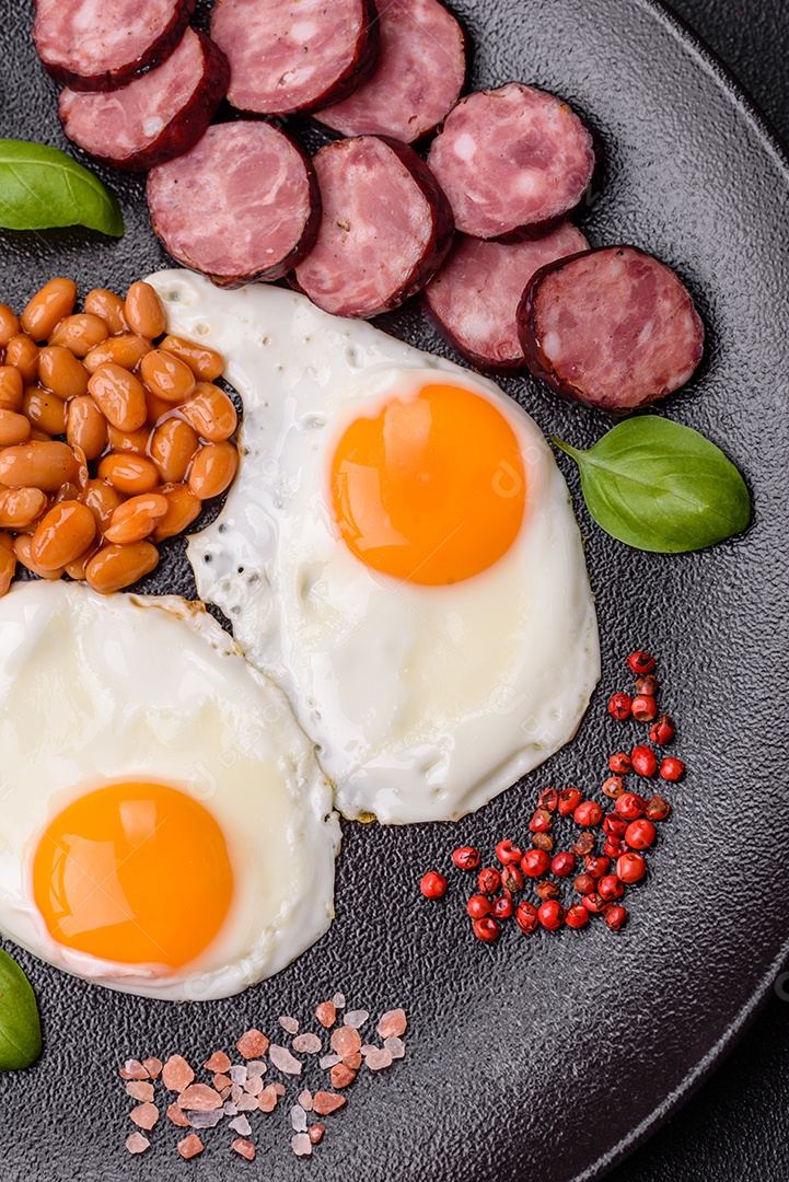 Café da manhã inglês com ovos fritos, bacon, feijão, tomate, especiarias e ervas. Um início de dia saudável e nutritivo