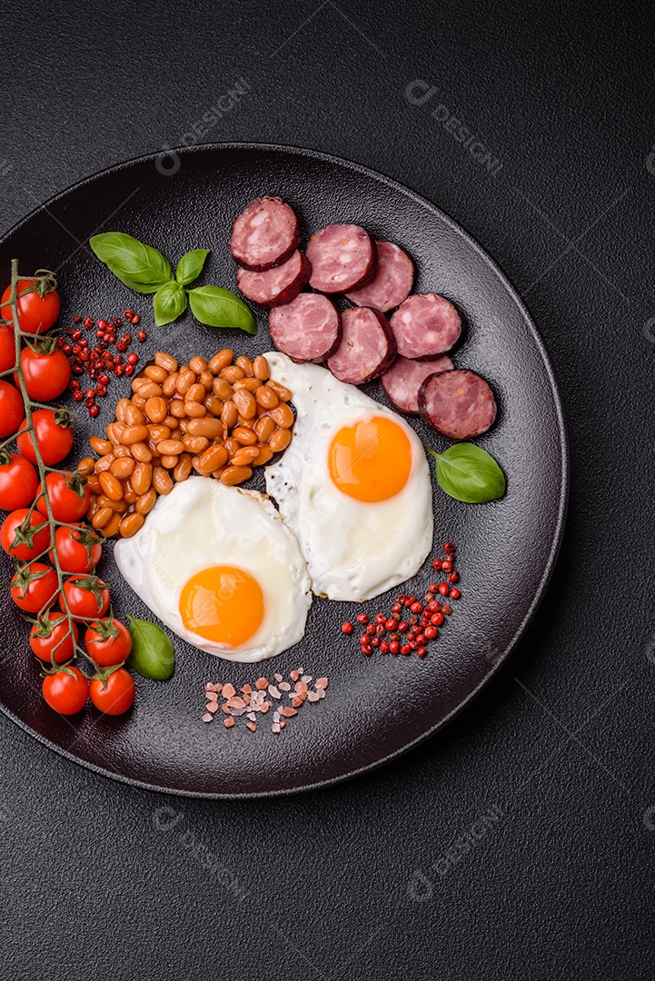 Café da manhã inglês com ovos fritos, bacon, feijão, tomate, especiarias e ervas. Um início de dia saudável e nutritivo