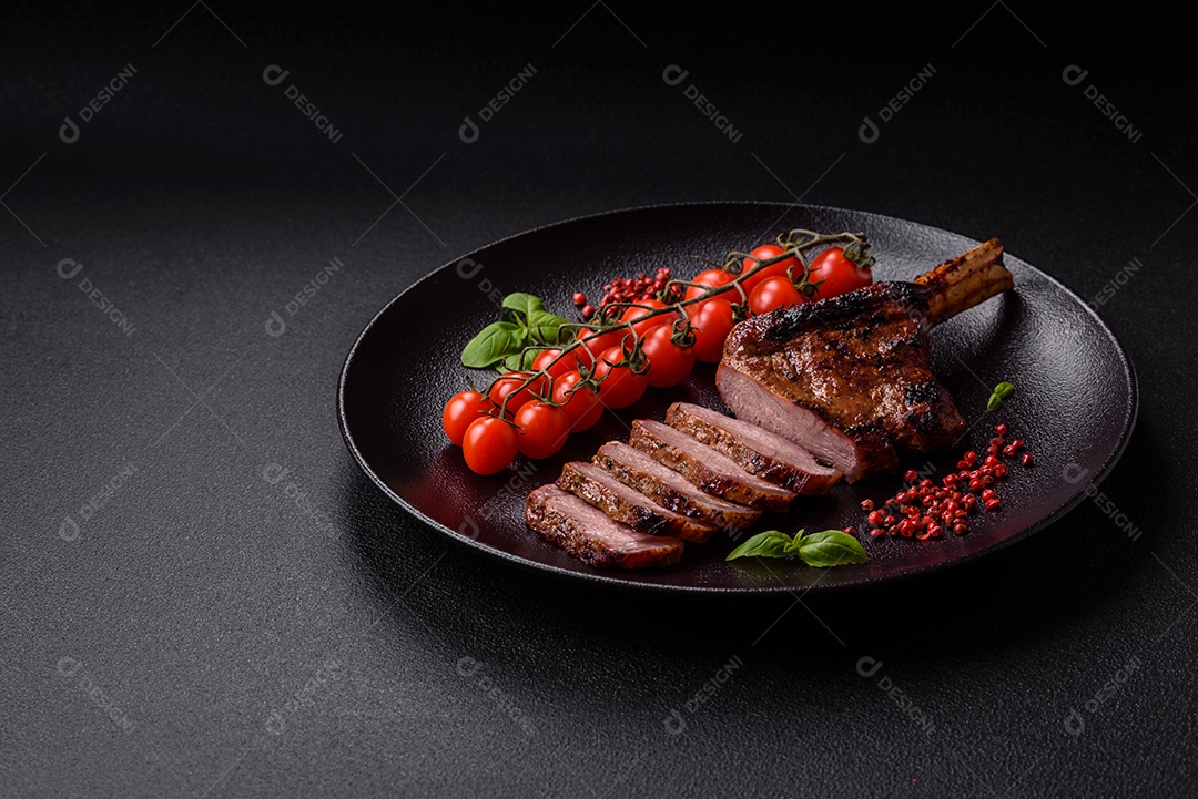 Delicioso bife de porco suculento com sal, especiarias e ervas sobre um fundo escuro de concreto